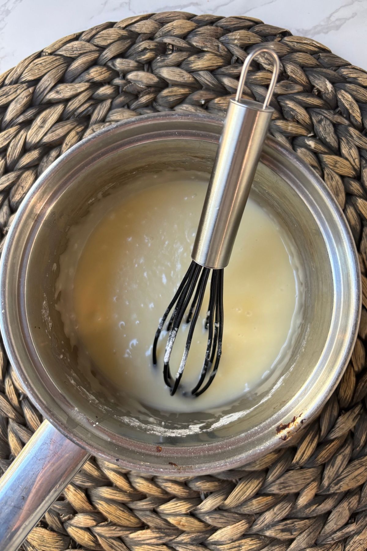 lemon frosting in a pot with a whisk.